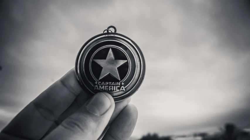 a person holding a medal with a star on it, a black and white photo, unsplash, american romanticism, marvel comics dslr hdr, avatar image, captain america, 🕹️ 😎 🔫 🤖 🚬