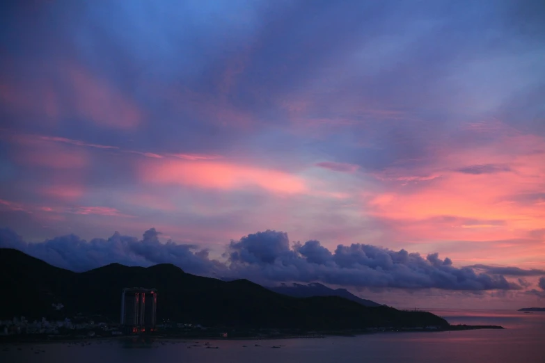 a large body of water under a cloudy sky, a picture, flickr, kowloon, redpink sunset, (((colorful clouds))), late summer evening