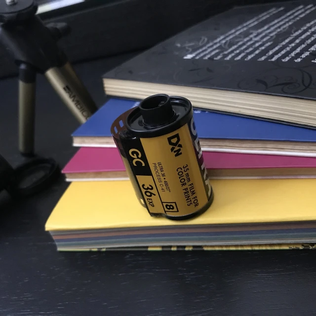 a roll of film sitting on top of a stack of books, a picture, battery, 35840k film, caught in 4 k, 3 6 0 p