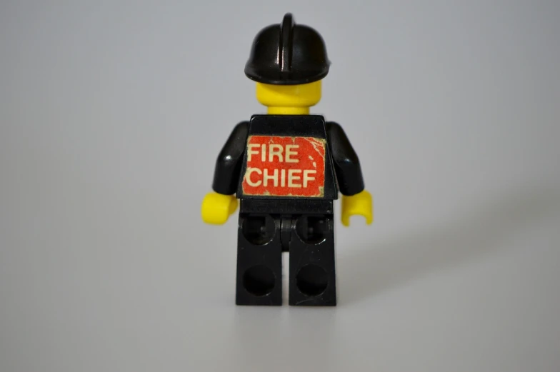 a lego man wearing a fire chief t - shirt, a picture, pexels, bauhaus, back, etsy, annie leibowit, label