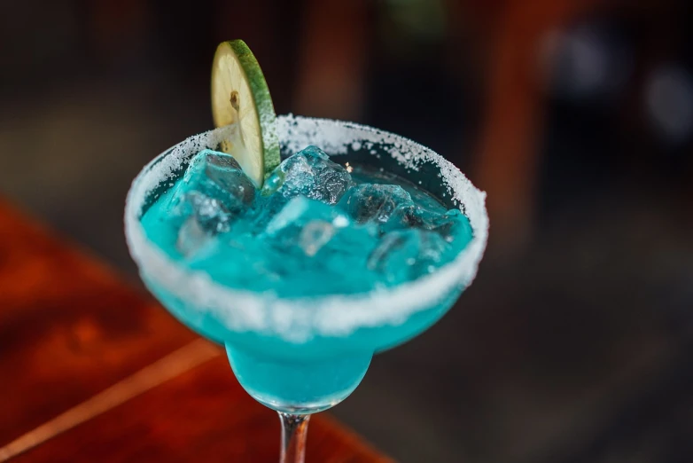 a blue drink sitting on top of a wooden table, by Rhea Carmi, pexels, mexican, 🍸🍋, server, competition winning