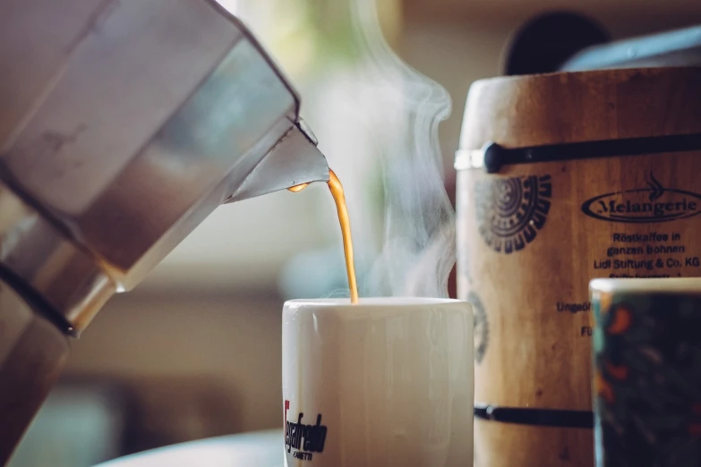 a cup of coffee being poured into a mug, a picture, by Jakob Gauermann, shutterstock, soft natural light, shot with sigma f / 4. 2, manuka, fully covered