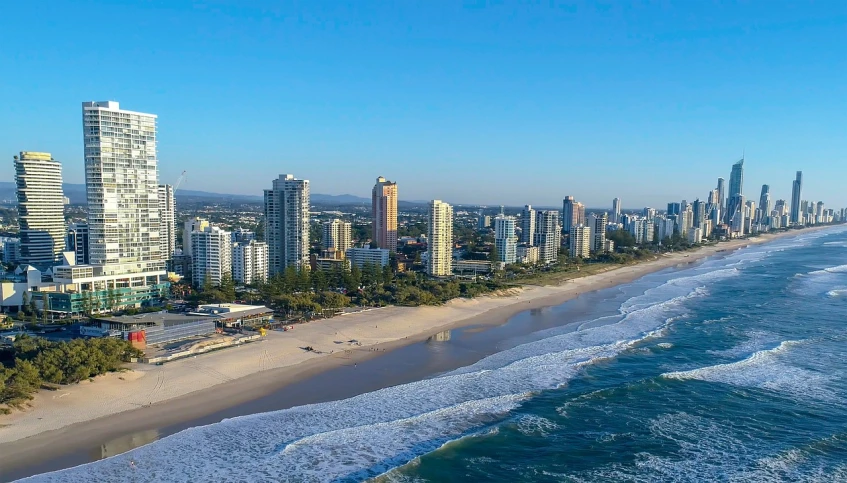 a view of a beach with a city in the background, by Seb McKinnon, pexels, helicopter footage over city, gold coast australia, instagram story, koyaanisqatsi