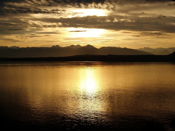 a large body of water under a cloudy sky, a picture, by Alexander Runciman, flickr, gold glow, washington state, shiny skin”, “ golden chalice