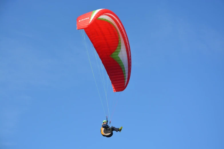 a person that is in the air with a parachute, a picture, by Erwin Bowien, shutterstock, red and green color scheme, in style of thawan duchanee, in scotland, in sunny weather