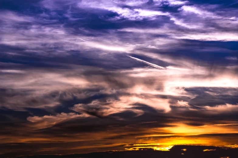 a plane flying through a cloudy sky at sunset, romanticism, violet and yellow sunset, ceremonial clouds, whorl. clouds, autumn sunset