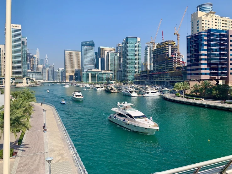 a number of boats in a body of water near a city, a picture, by Bernardino Mei, pexels, hurufiyya, gta : dubai, slightly sunny weather, taken on iphone 1 3 pro, all buildings on bridge