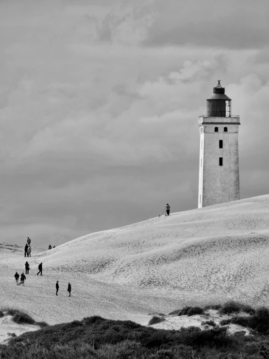 a black and white photo of people walking towards a lighthouse, by Andrei Kolkoutine, pexels contest winner, snow dunes, summer light, treasures, pastel