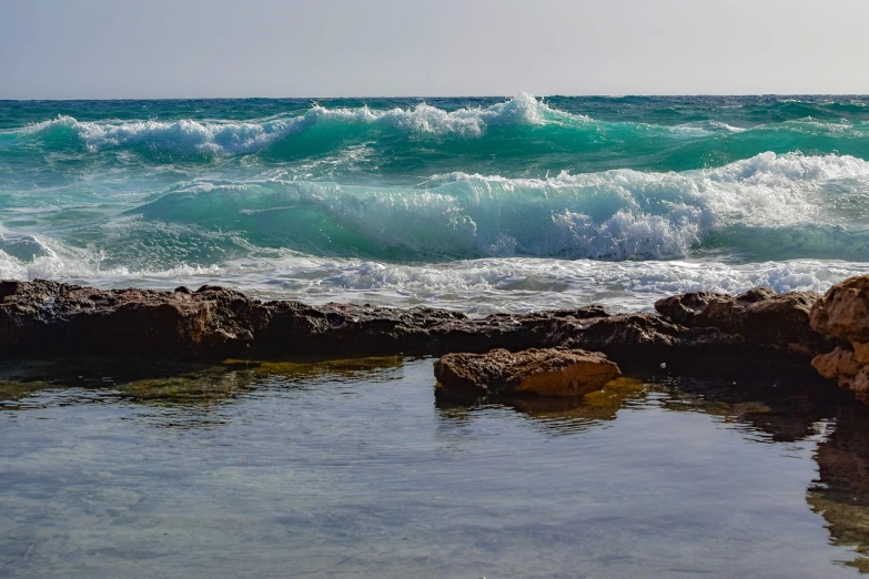 a body of water that has some rocks in it, a picture, by Leo Michelson, shutterstock, cresting waves and seafoam, mediterranean beach background, varadero beach, shot on nikon z9