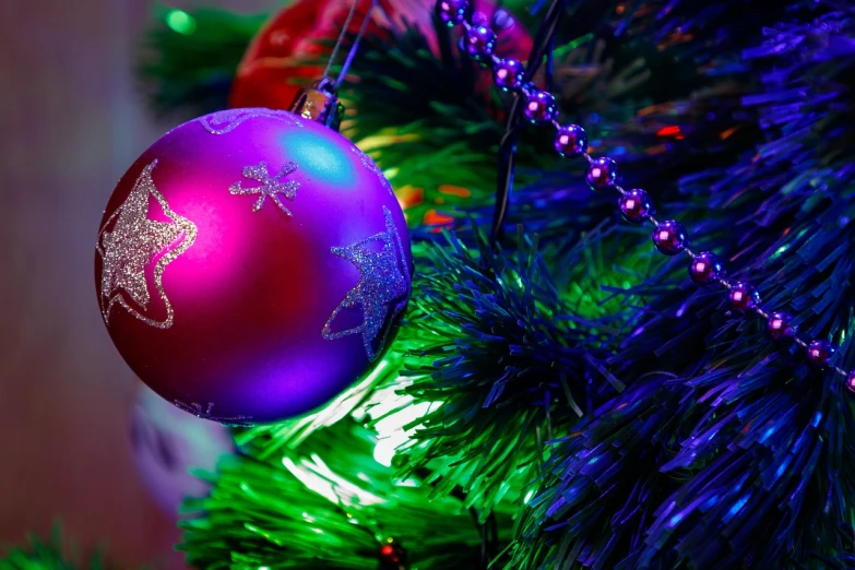 a purple ornament hanging from a christmas tree, a photo, by Kazimierz Wojniakowski, shutterstock, background colorful, good lighted photo, background image, blue and green and red tones