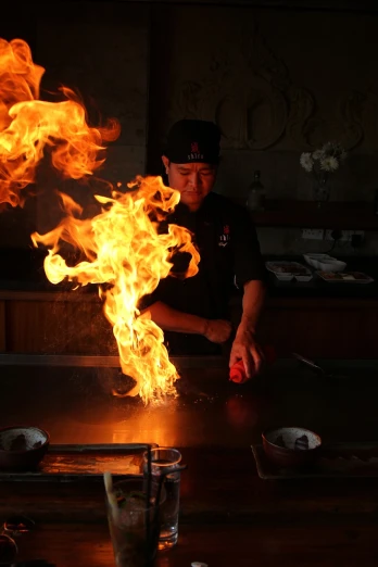 a man that is standing in front of a fire, a picture, by Robbie Trevino, japanese fusion cuisine, usa-sep 20, the photo shows a large, professional foto