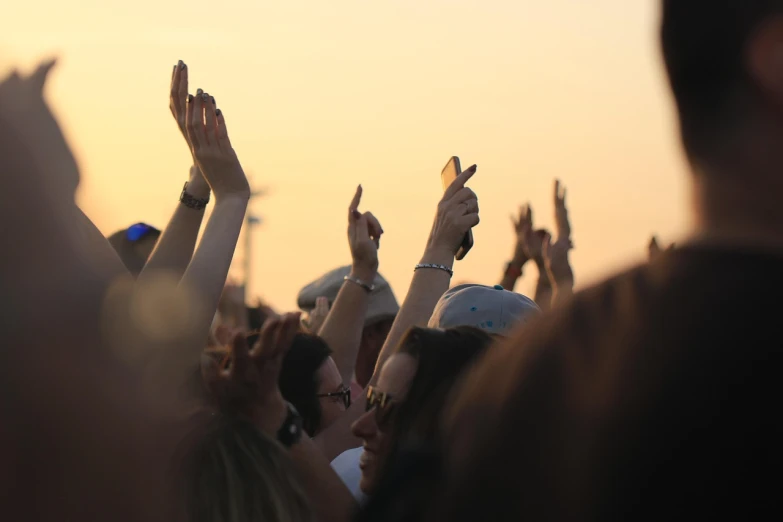 a crowd of people raising their hands in the air, pexels, golden hour closeup photo, horns!, watch photo, wikimedia