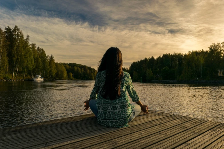 a woman sitting on a dock next to a body of water, a picture, anjali mudra, trending photo, sittin