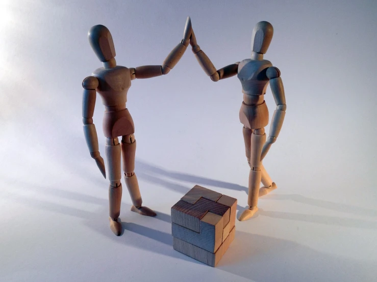 a couple of wooden dolls standing next to each other, a picture, figurativism, shaking hands, cube shaped, pudica pose gesture, joints