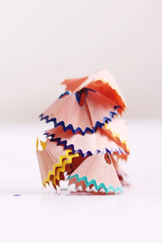 a pile of colored pencils sitting on top of a white surface, by Martina Krupičková, crayon art, ruffles, kirigami, peach embellishment, stopmotion