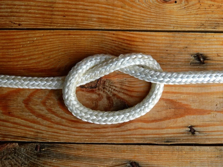 a close up of a rope on a wooden surface, inspired by Kanō Shōsenin, white finish, very sharp photo, celtic knot, portlet photo