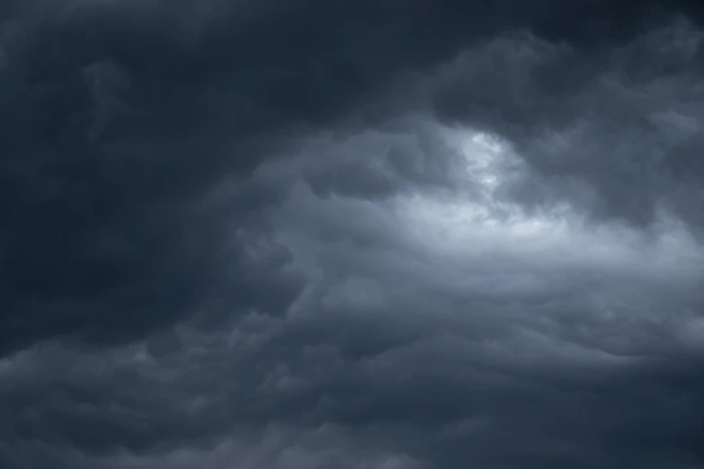 a large jetliner flying through a cloudy sky, a picture, by Steven Belledin, dark stormy dramatic sky, whorl. clouds, dark and dim, tumultuous