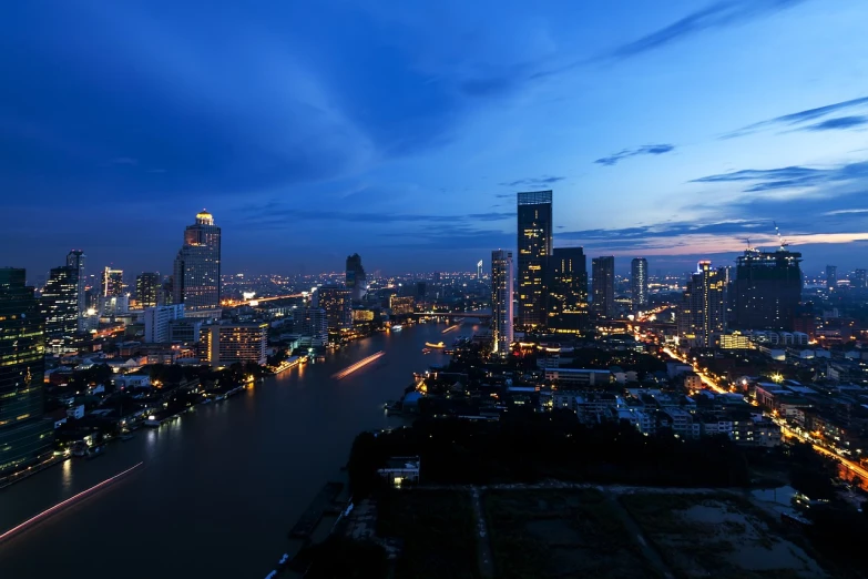 a river running through a city next to tall buildings, by Bernardino Mei, shutterstock, bangkok, blue sunset, light from top, nightshot