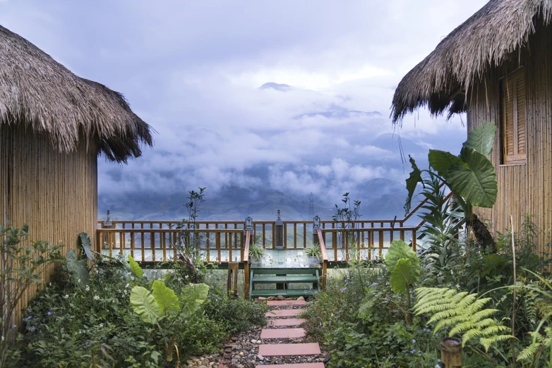 a couple of huts sitting on top of a lush green field, shutterstock, low clouds after rain, beautiful terrace, conde nast traveler photo