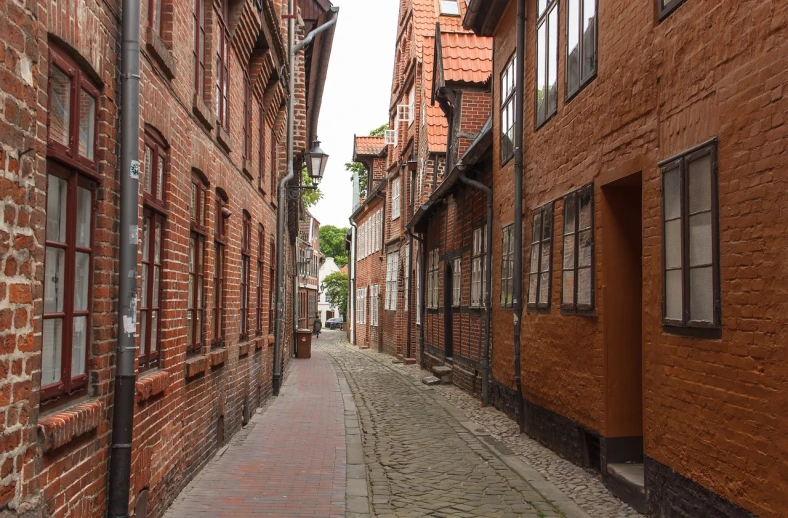 a narrow street is lined with brick buildings, a picture, by Troels Wörsel, shutterstock, lower saxony, wooden buildings, stock photo