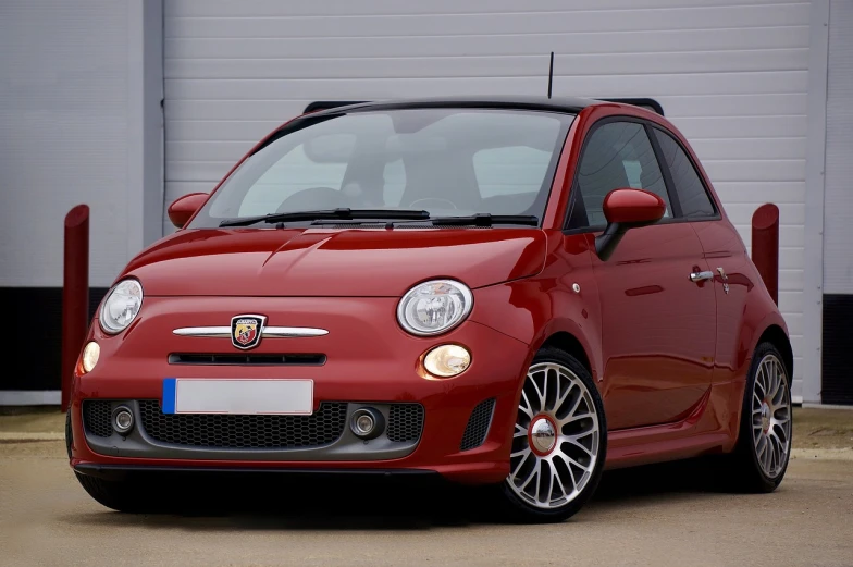 a small red car parked in front of a garage, inspired by Francesco Filippini, pixabay, renaissance, red short hair, crimson - black beehive, convertable, spartan