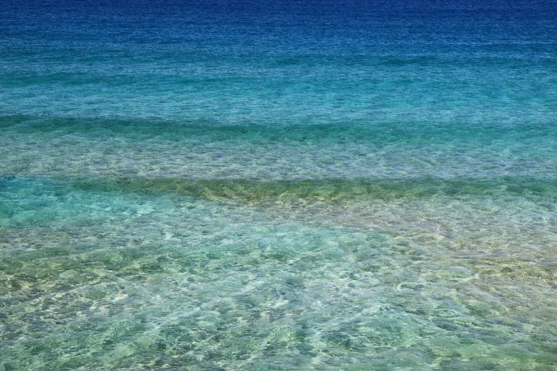 a person riding a surf board on top of a body of water, by Richard Carline, flickr, minimalism, coral sea bottom, water refractions!!, deep colours. ”, island in a blue sea