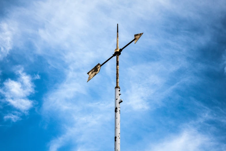 a weather vane sitting on top of a metal pole, postminimalism, deteriorated, arrow shaped, hd photo, with two arrows