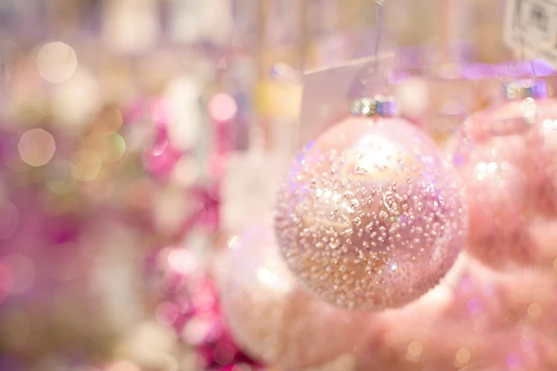 a close up of a person holding a christmas ornament, by Maeda Masao, romanticism, soft light 4 k in pink, bokeh photo, mall background, pearlized