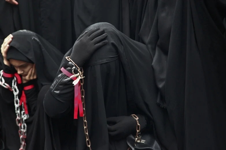 a group of women dressed in black standing next to each other, a photo, by Eva Gonzalès, tumblr, hurufiyya, chains broken on hands, red and black flags, detailed face of an arabic woman, faceless people