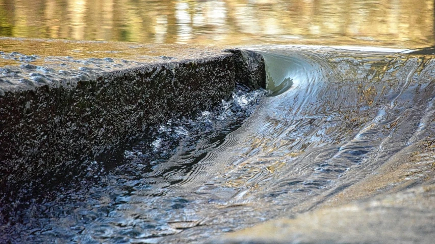 a close up of a wave in a body of water, by Jan Rustem, shutterstock, storm drain, flowing clear water creek bed, photograph taken in 2 0 2 0, looking to the right