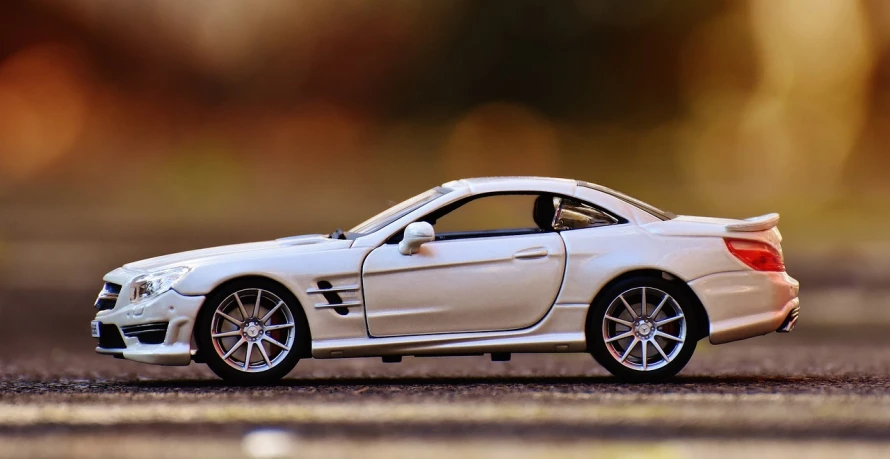 a white toy car sitting on top of a parking lot, pexels contest winner, photorealism, miniature of a sports car, mercedes, side view profile, car on highway