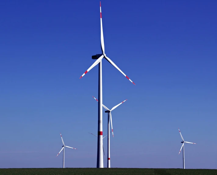 a group of wind turbines sitting on top of a green field, bauhaus, blue clear skies, ƒ/2.5, monitor, mines