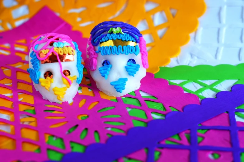 a couple of sugar skulls sitting on top of a table, a portrait, by Fiona Rae, process art, play - doh, colourful close up shot, 3 d printing, 3 spring deities