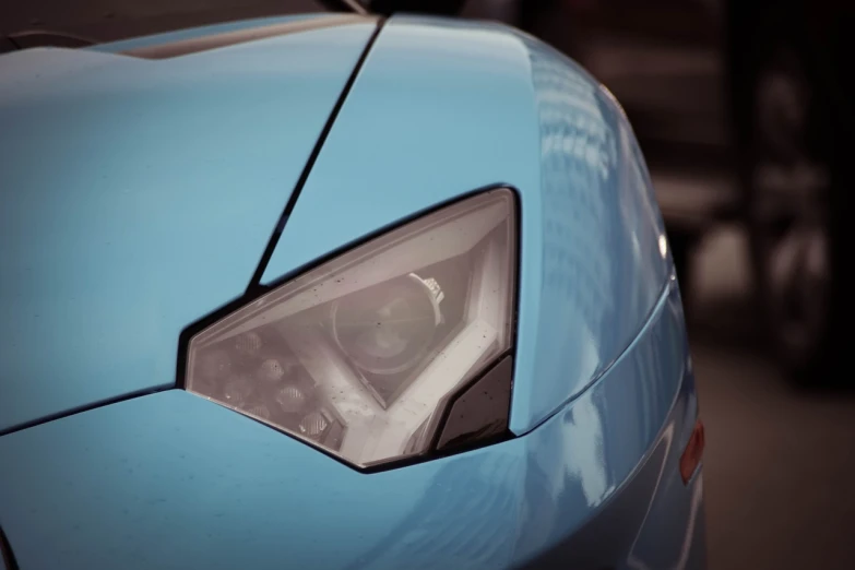 a close up of the headlight of a blue sports car, a picture, by Thomas Häfner, unsplash, photorealism, light blue skin, lamborghini aventador photoshoot, taken with my nikon d 3, closeup of an adorable