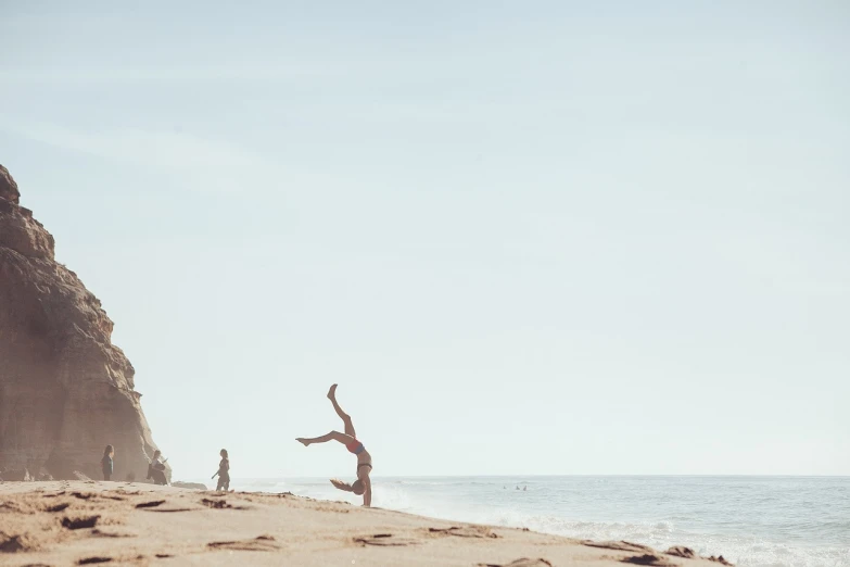 a person jumping in the air on a beach, a picture, by Caro Niederer, arabesque, kids playing at the beach, victoria siemer, yoga, landscape wide shot