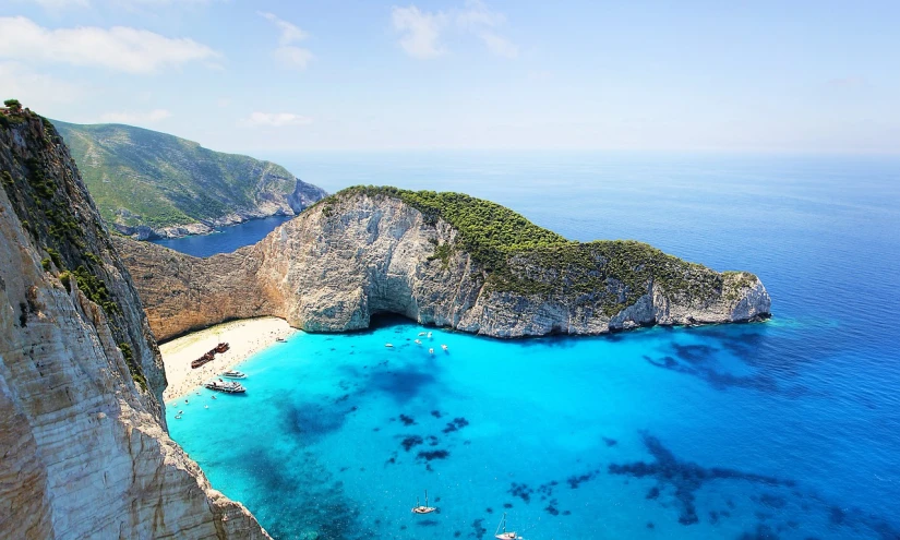 a large body of water next to a cliff, by Alexis Grimou, pixabay, white beaches, alexandros pyromallis, blue colored, well edited