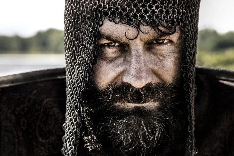 a close up of a man wearing a chainmail hat, a portrait, by Konrad Krzyżanowski, shutterstock, an epic viking battle scene, in style of mike savad”, museum quality photo, black curly beard