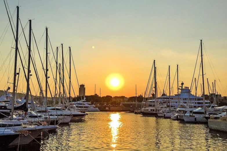 a number of boats in a body of water, a picture, by Tom Wänerstrand, pexels, city sunset, with a bright yellow aureola, on a super yacht, harbour in background