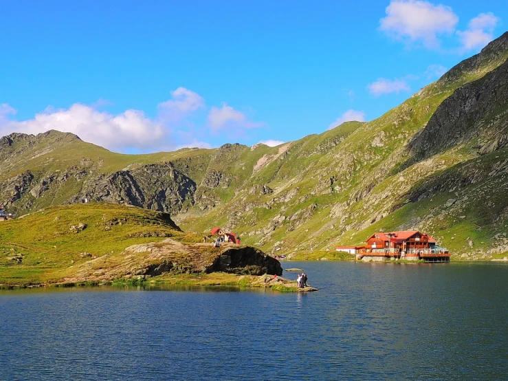 a large body of water surrounded by mountains, by Alexander Bogen, shutterstock, art nouveau, huts, romanian heritage, shot with iphone 1 0, red lake