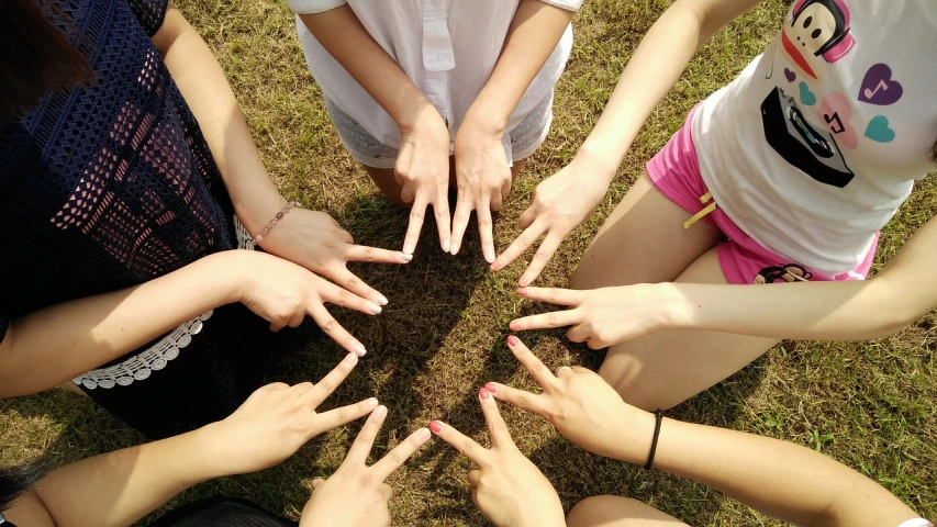 a group of people making a circle with their hands, by Tom Carapic, precisionism, young girls, sunny summer day, pentagrams, low quality photo