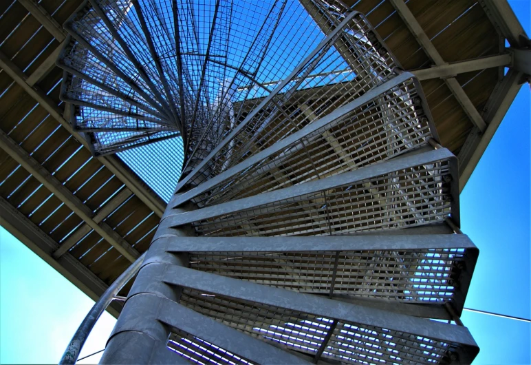 a spiral staircase going up to the top of a building, inspired by Edwin Georgi, flickr, netting, lookout tower, taken with my nikon d 3, exposed inner structure