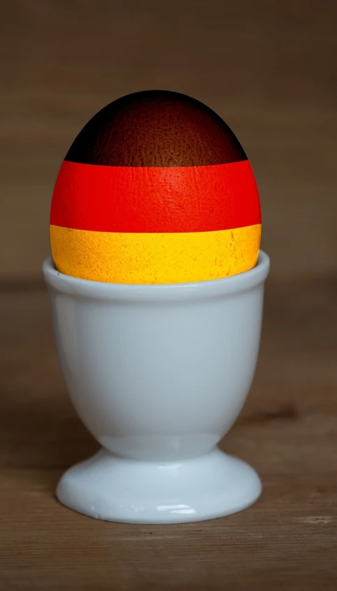 a wooden egg sitting on top of a white bowl, a stock photo, by Thomas Häfner, pexels, bauhaus, flag, german, miniature product photo, stroopwaffel