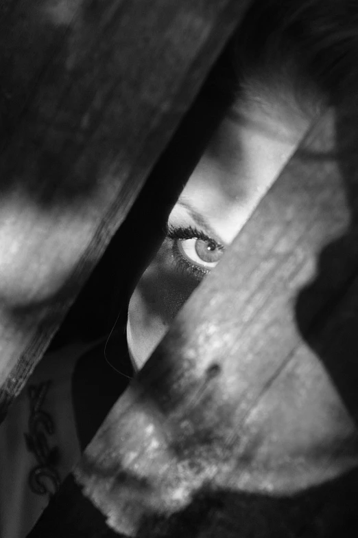 a black and white photo of a close up of a person's face, pixabay, surrealism, hiding behind obstacles, a wooden, spying, mysterious girl