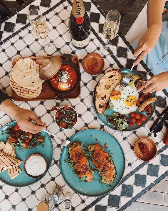 a group of people sitting at a table with plates of food, by Emma Andijewska, pexels, hearty breakfast, azure and red tones, 🦩🪐🐞👩🏻🦳, flat lay