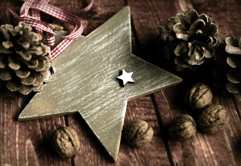 a wooden star sitting on top of a wooden table, a photo, inspired by Ernest William Christmas, shutterstock, folk art, nut, ribbon, old color photo, walnut wood