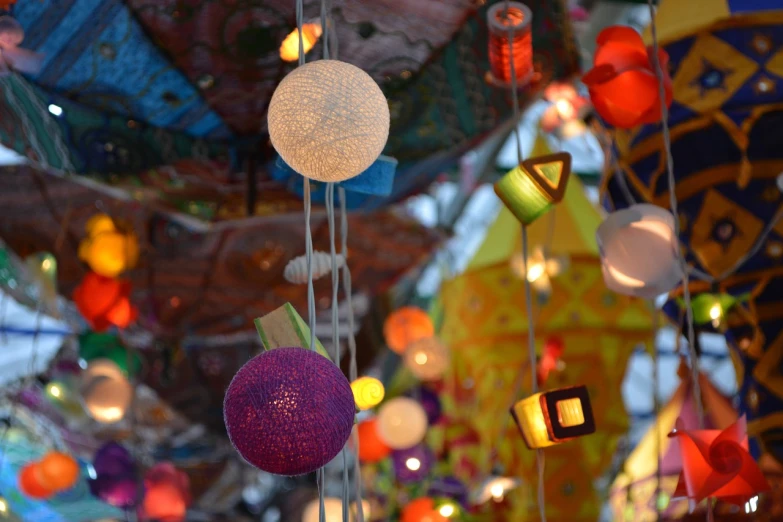 a bunch of paper lanterns hanging from a ceiling, a picture, by Erwin Bowien, pexels, maximalism, neon lights outside, glittering multiversal ornaments, wind chimes, really detailed
