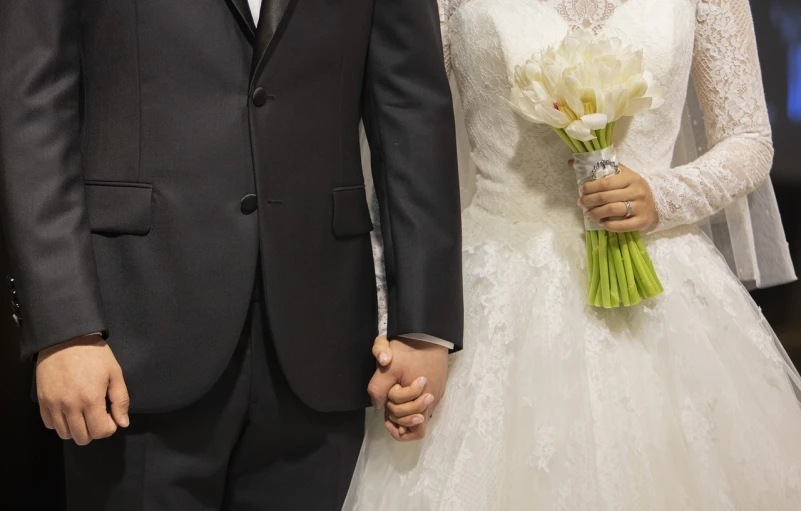 a bride and groom hold hands as they walk down the aisle, by Jaakko Mattila, pixabay, afp, closeup of arms, istockphoto, bouquet