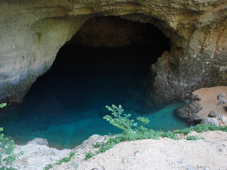 a cave filled with water next to a lush green hillside, flickr, les nabis, cobalt coloration, located in hajibektash complex, beutiful!, light blue water