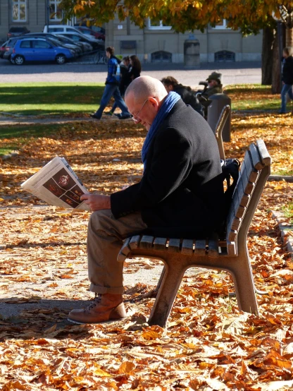 a man sitting on a bench reading a newspaper, a photo, in fall, photo - shot, gary, some people are sitting