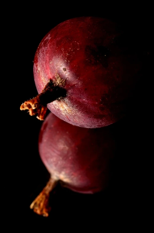 a red apple sitting on top of a black surface, a macro photograph, inspired by Jacopo Bassano, beets, grape, portait photo